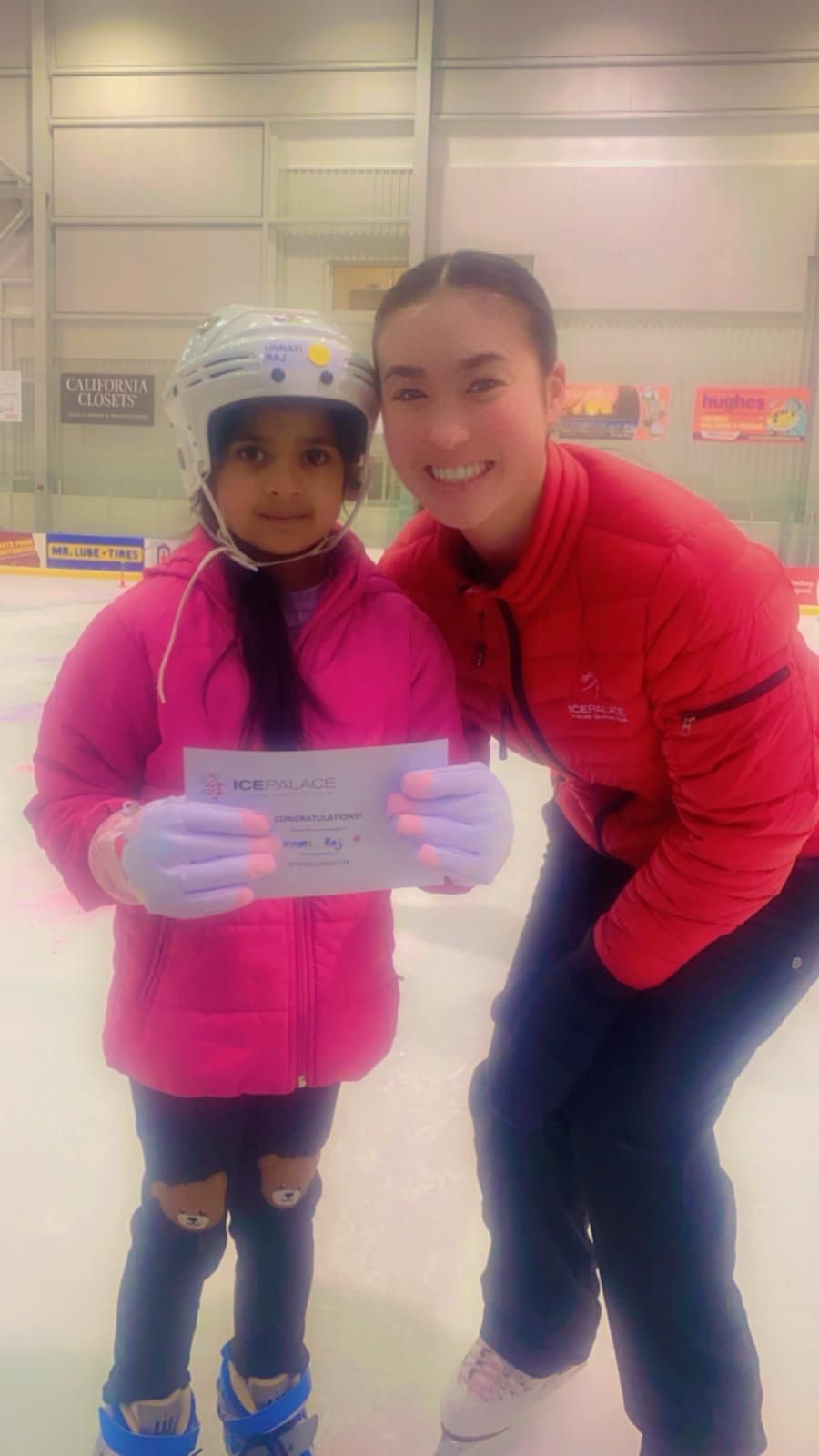 Unnati Raj holding her skating certificate beside her coach at the rink